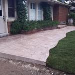 Coloured concrete sidwalk with new sod, and a lightpost on a concrete pad.