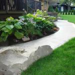 Armour stone, landscaped garden, and a new concrete sidewalk leading to the new patio for the spa.