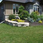 Armour stone edging around beautiful landscaped garden in front of this luxury home.