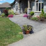 Grey stamped concrete sidwalk leading up to front door of house.