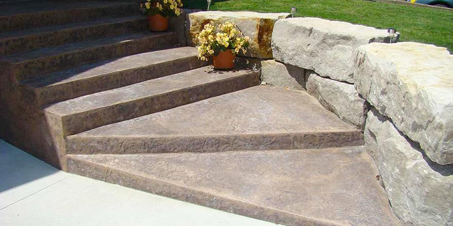 Stamped concrete steps with armour stone retaining wall.