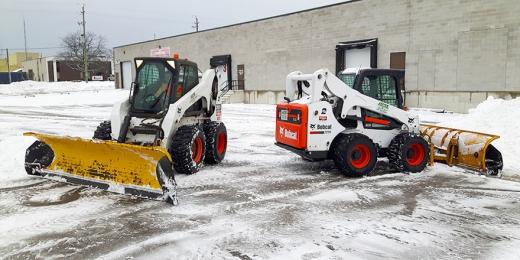 Snow plows clearing snow from a parking lot.